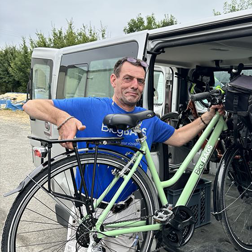 Nicolas in a blue t-shirt loading a bicycle into his truck